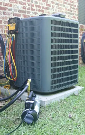 Outdoor air conditioning condenser beside a brick house