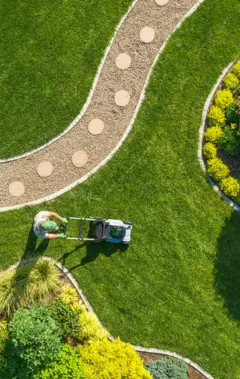 Aerial view of a lawn being mowed beside a garden path
